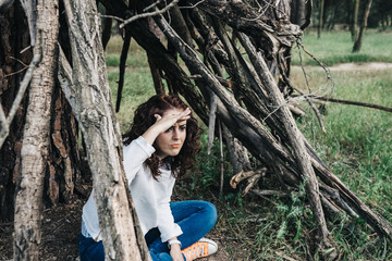 Young beautiful woman playing in the park in a cottage made with wooden trunks as when she was a child. Lifestyle portrait.