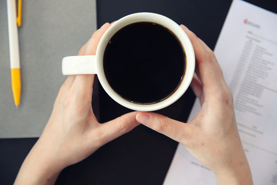 woman hand drinking coffee with business paper