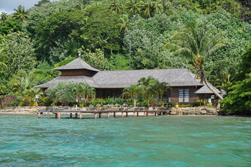 Waterfront tropical house with green vegetation on the seashore of Huahine island, French Polynesia, south Pacific
