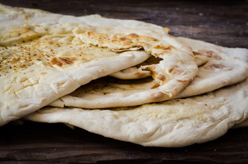 Closeup Homemade freshly baked Flatbread - Middle Eastern multi seeded flatbread with seasame seeds on woode3n background. Toned image