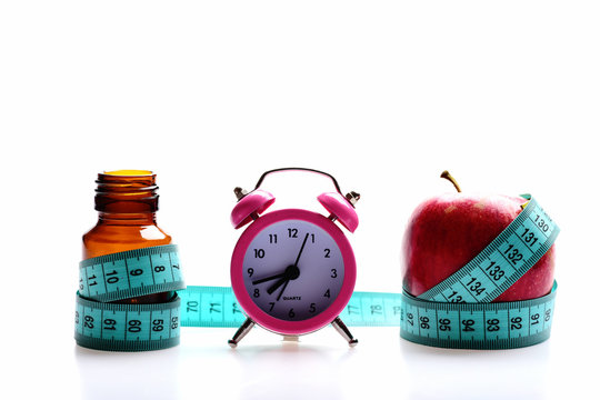 Concept of diet and regime: alarm clock, bottle and apple