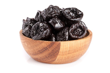 Dried plums or prunes in wooden bowl isolated on white background