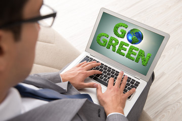 Businessman with laptop in green environment concept