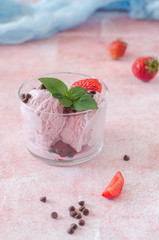 Portion of Strawberry ice cream with chocolate drops in glass on stone background. Selective focus