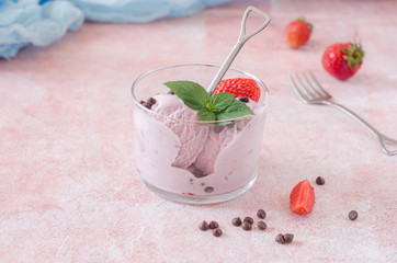 Portion of Strawberry ice cream with chocolate drops in glass on stone background. Selective focus
