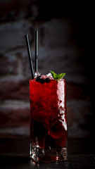 Berry (currant) lemonade with mint and ice on a dark background.