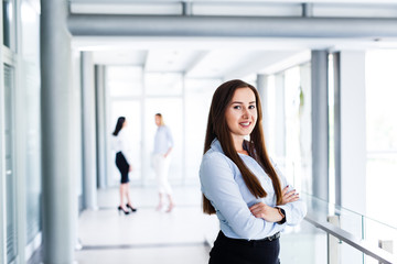 Attractive business woman standing and crossing her arms while behind are standing her work colleague