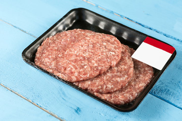 Raw minced meat burgers in the market package with price tag