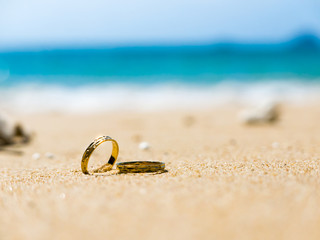 Honeymoon. Two wedding rings on sandy beach