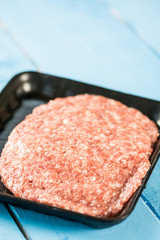 Minced meat burgers in the market package above wooden background