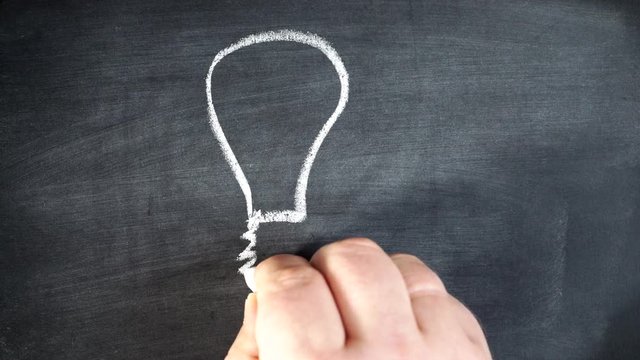 Male hand drawing light bulb on chalkboard. Creativity concept 4K ProRes HQ codec