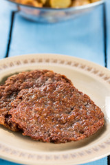 Fried minced meat burgers served on the plate above wooden blue boards