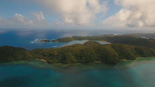 Aerial view tropical island with the mountains and the rainforest on a background of ocean. Aerial footage, sea and the tropical island with rocks, beach and waves. Seascape: sky, clouds, rocks, ocean