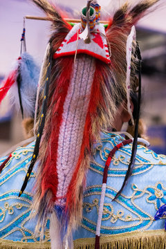 Headdress from the Back worn by a Native American man at a pow wow. The headdress has woven portions and is decorated with feathers.