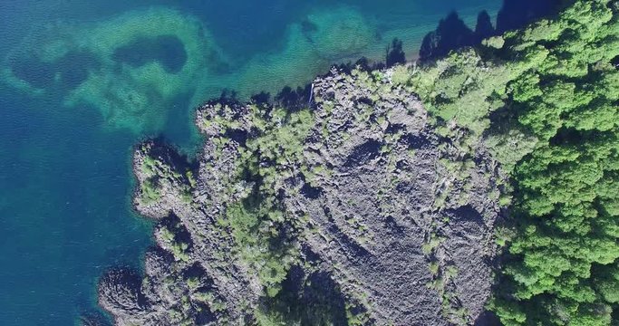 Aerial drone scene top view of green lake in south Patagonia, Argentina. Wild woods and cost of lake with dark volcanic sand and lava from a volcano, camping.