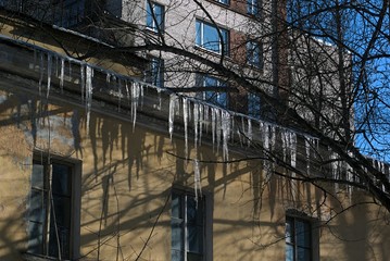 Many hanging icicles from the metal roof of the old house.