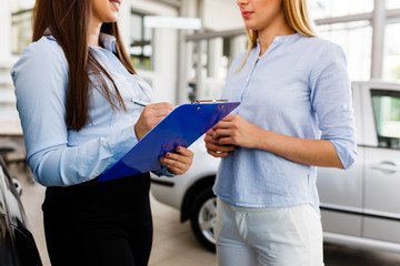 Two women makeing a agreement in modern car dealership