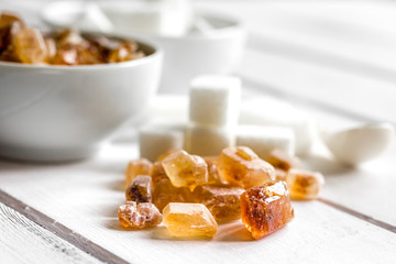lumps of white and brown sugar on white wooden table background