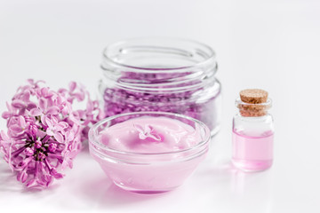 lilac cosmetics with flowers and spa set on white table background