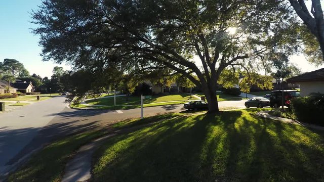 Aerial view of the front yard with a street sign and sunlight coming through tree branches
