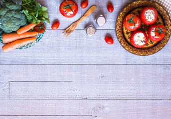 Stuffed tomatoes with cheese, and different vegetables, on a wooden background,