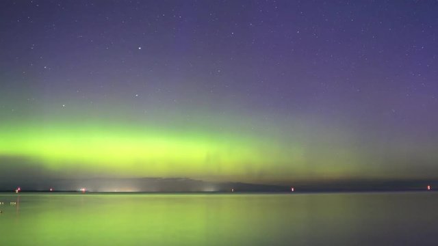 Northern light aurora borealis dancing over water in night sky until dawn in Ontario, Canada