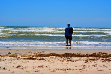 Looking to sea/Man standing in the shallow tide, looking out to sea