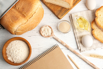 Composition with notebook and ingredients for bread on wooden table