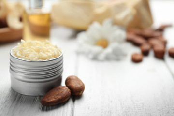 Jar with cocoa butter product and beans on table