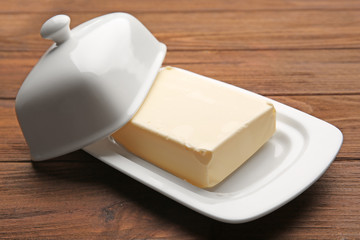 Dish with butter on wooden table