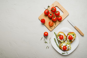 Fototapeta na wymiar Italian bruschetta with soft cheese, tomatoes, rosemary and fresh salad on the plate. Space for text