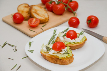 Italian bruschetta with soft cheese, tomatoes, rosemary and fresh salad on the plate. Space for text