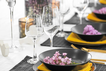 Beautiful table setting with black plates and lilac as floral decor