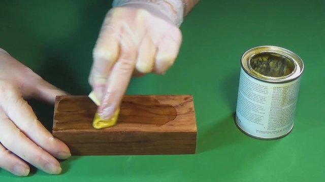 Wood beam palisander. The bar of solid wood is covered with stain. The girl covers a bar of rare wood with lacquer. The joinery impregnates the wood with wax. Chroma Key.