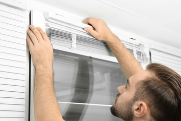 Man installing window blinds at home, close up