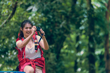 Beautiful young young woman with backpack taking photographs the beautiful landscape in forest at summer