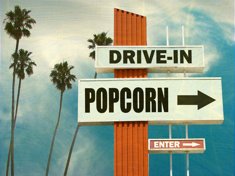 aged and worn vintage photo of drive in popcorn sign with palm trees
