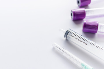 closeup blood sample tubes and syringe on white background. soft-focus and over light