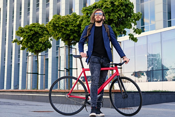 A man with backpack sits on the red fixed bicycle.