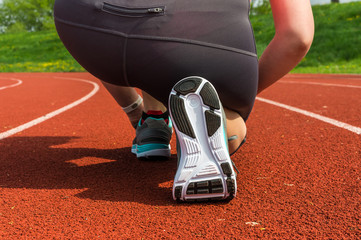 Woman is lacing her shoes on a stadium running track
