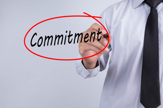 Businessman Hand Writing commitment with a marker over transparent board, Business concept.