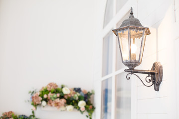 Vintage iron lantern on the wal outdoor. Garden metal electrical lamp in a village