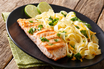 Healthy food: grilled salmon and fettuccine pasta with cheese and herbs close-up. horizontal