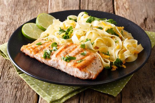 Pasta fettuccine with cheese and butter and grilled salmon with herbs close-up. horizontal