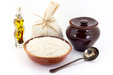 The composition of Rice groats in a clay pial next to a clay pot and a copper spoon,