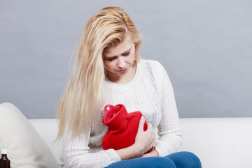 Woman feeling stomach cramps sitting on cofa