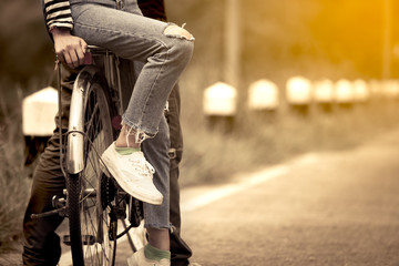 Leg and feet of young couple riding a bicycle together in vintage color tone