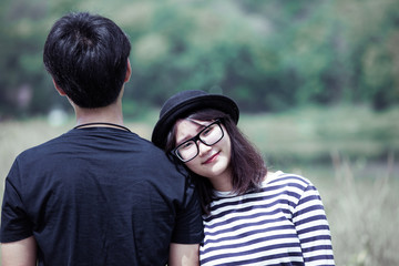 Asian young woman resting on her boyfriend's shoulder with love in outside in vintage color tone