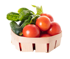 Tomatoes with cucumber and spinach leaves in a basket