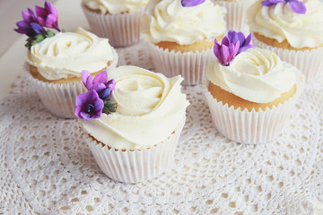 Rose flower frosting vanilla cupcakes with purple edible flowers